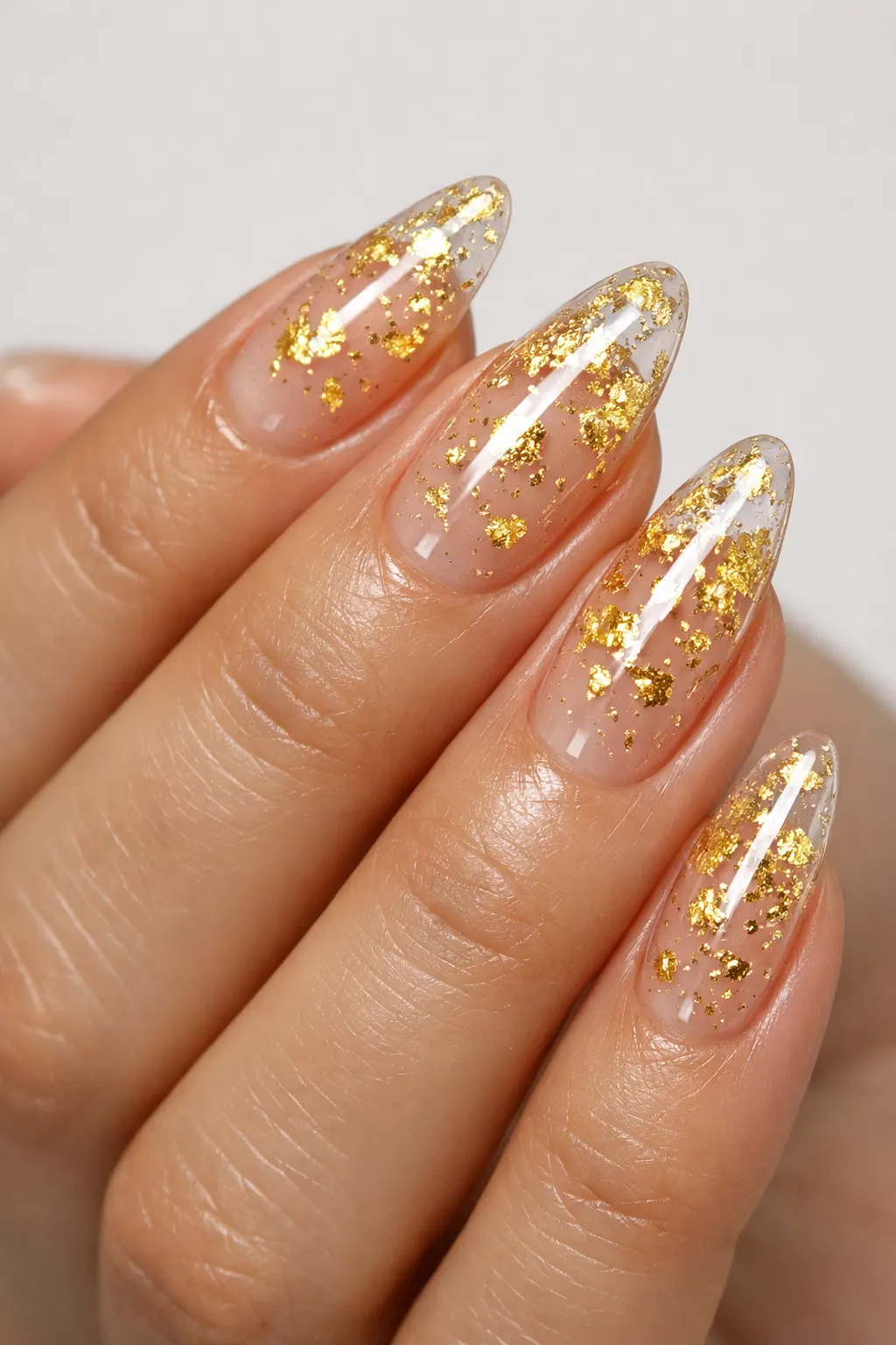Nude blooming gel nail art with gold foil flakes luxury glossy manicure design