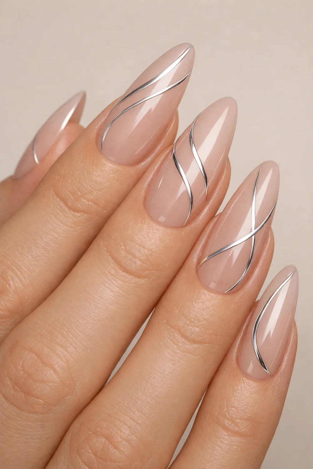 Elegant nude acrylic nails with flowing chrome swirl lines on almond shaped tips, glossy neutral manicure design that looks modern, classy, and perfect for stylish nail inspiration.