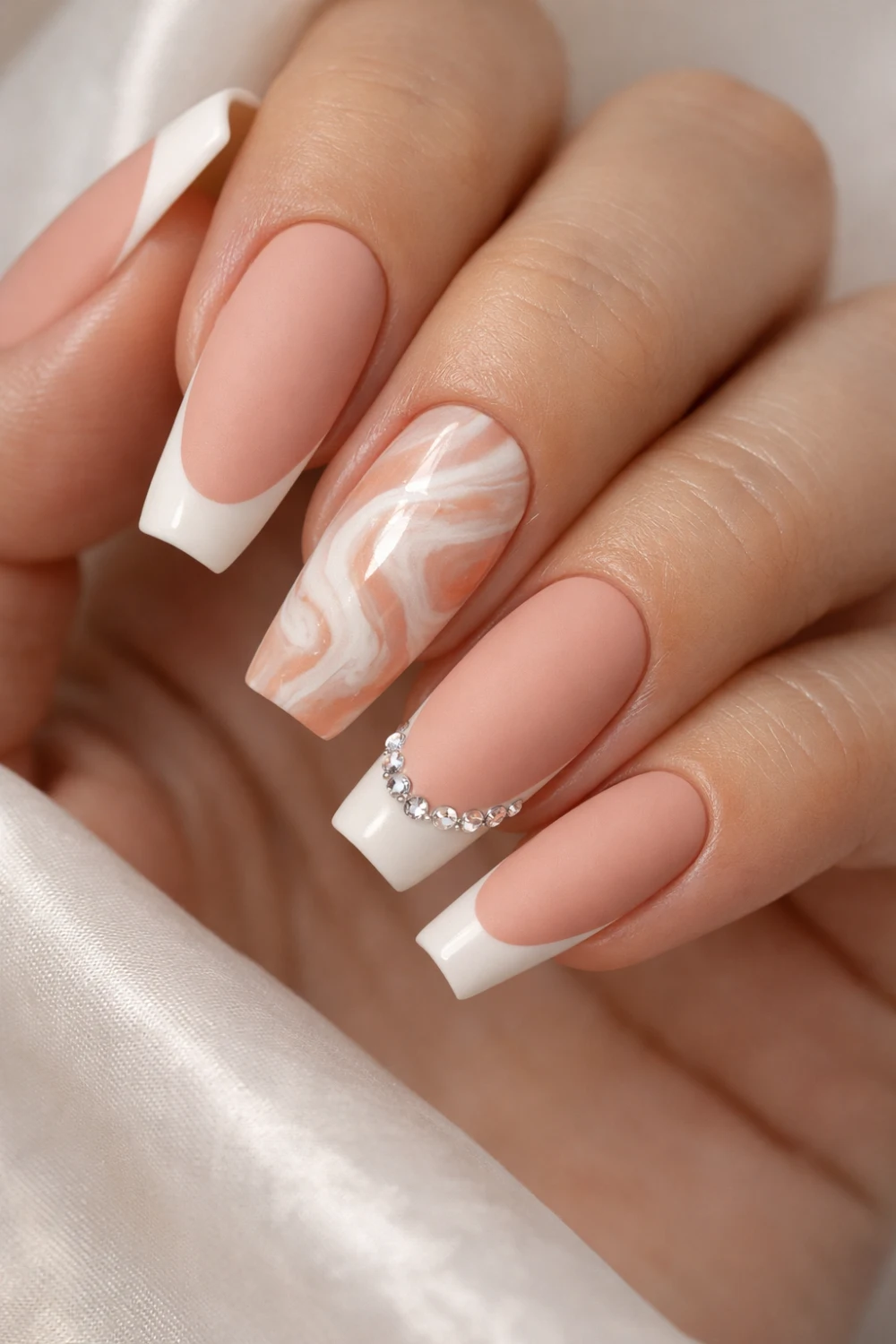 matte nude french tip nails with peach marble accent nail design and crystal curve detail on almond shaped manicure trendy matte nail inspiration