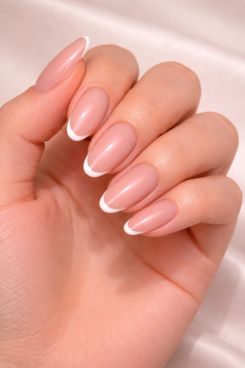 Classic french tip acrylic nails with nude pink base and clean white tips on almond shaped nails creating a timeless elegant manicure perfect for minimal nail inspiration.