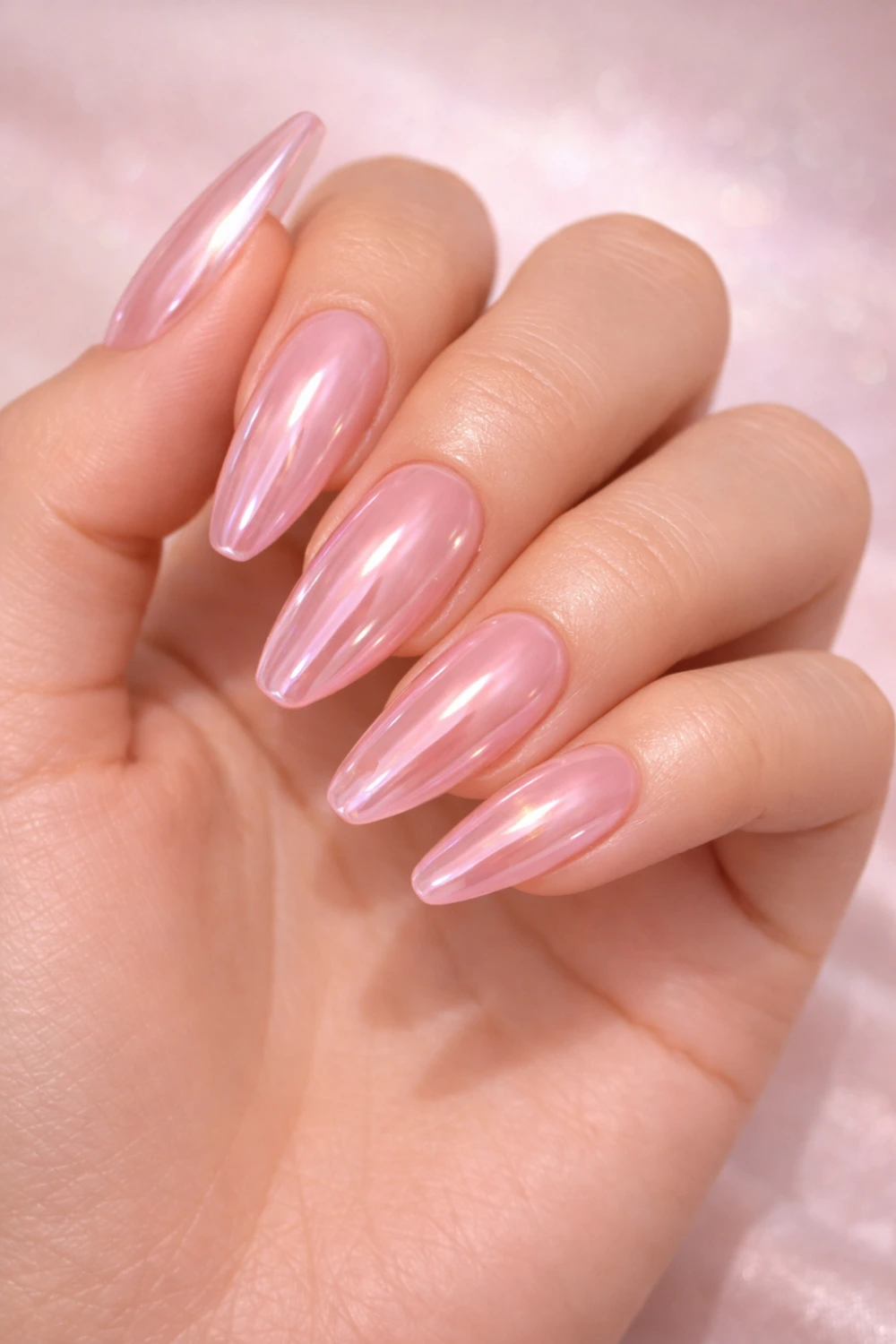 Glossy pink chrome acrylic nails with reflective metallic shine on long almond shaped nails creating a glamorous manicure perfect for trendy nail inspiration.