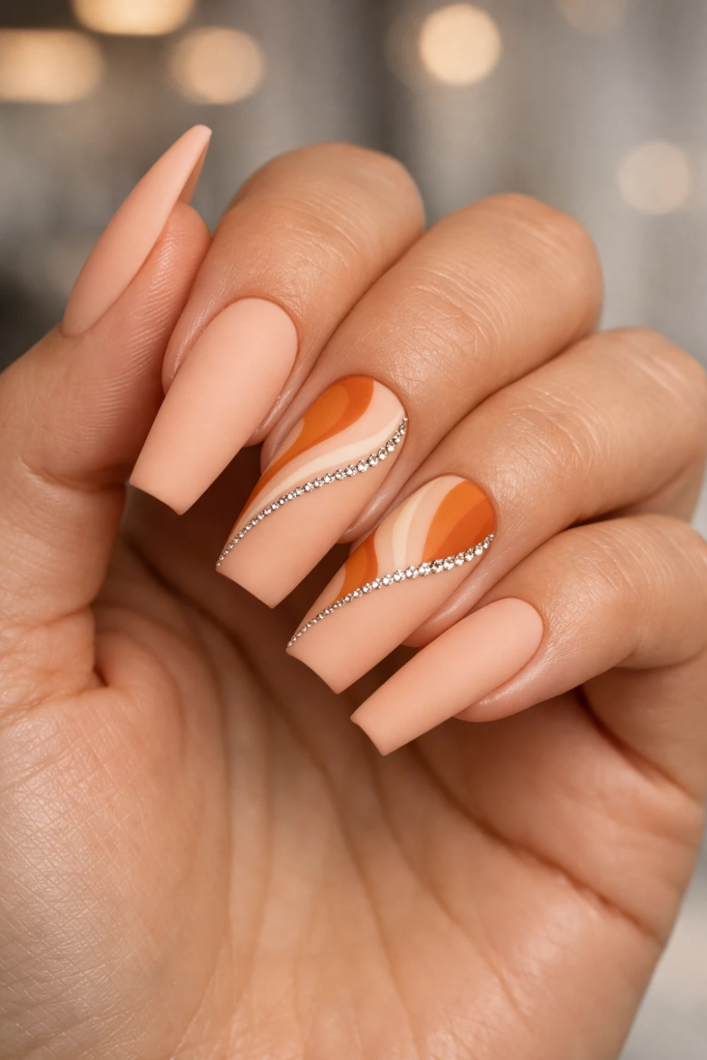 matte peach nails with abstract swirl nail art and crystal curve detail stylish almond manicure trendy matte nail inspiration