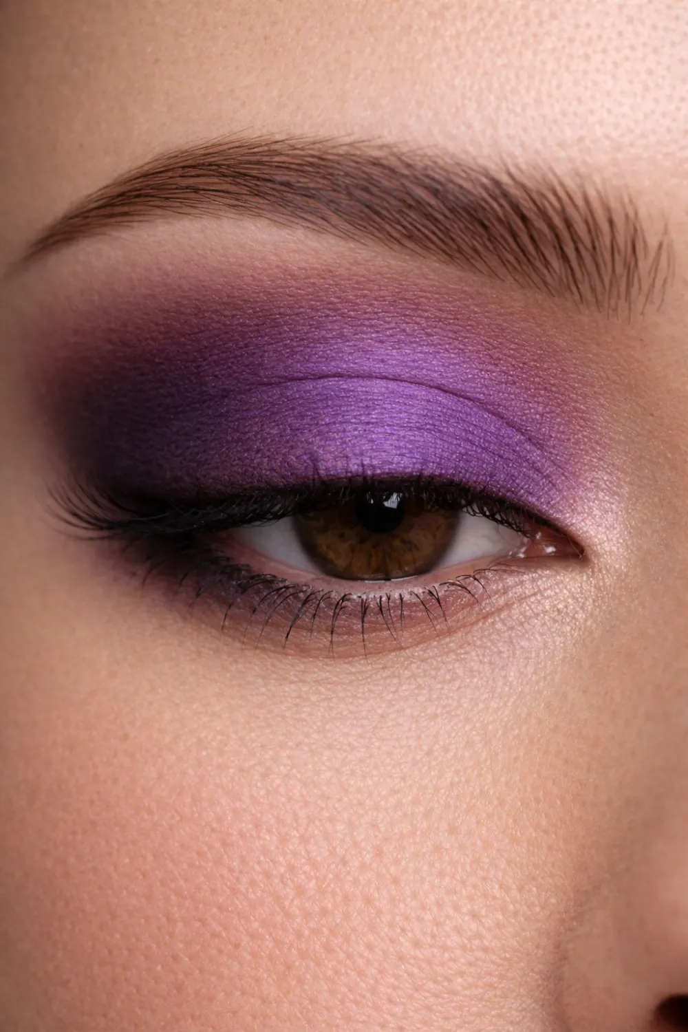 Bold purple eyeshadow look for brown eyes close up with vibrant violet lid and deep plum outer corner dramatic glam eye makeup