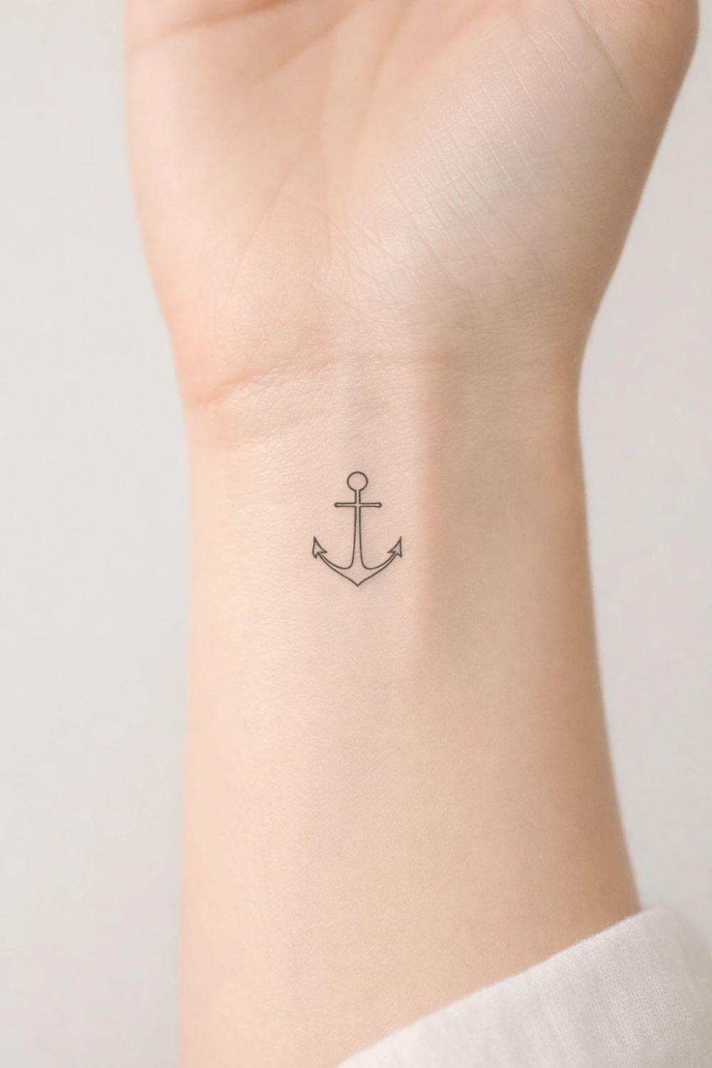 small anchor wrist tattoo in minimalist line style, simple nautical tattoo design symbolizing stability hope strength and staying grounded during life challenges