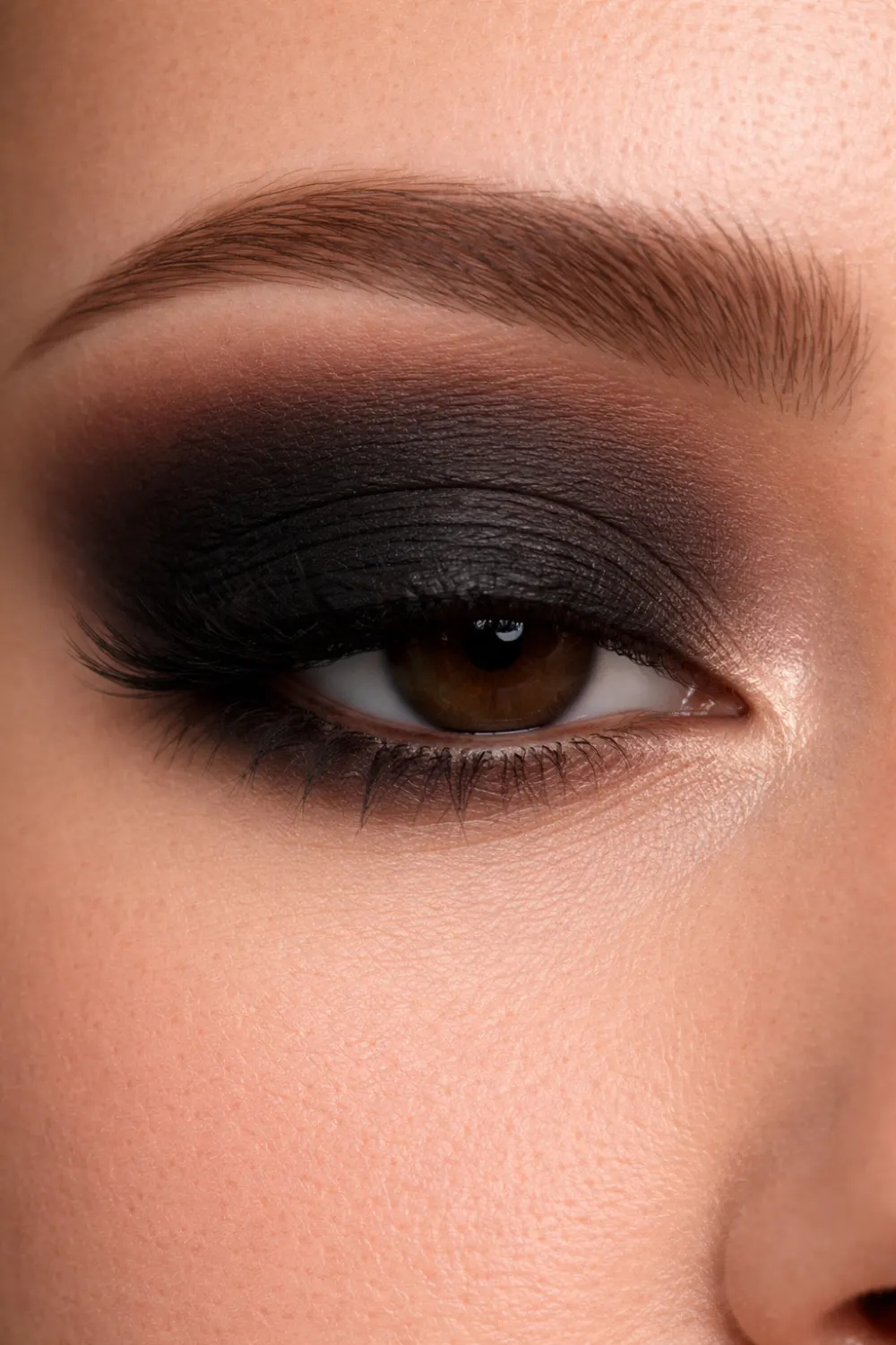 Classic black smokey eyeshadow look for brown eyes close up with deep black lid and smoky blended crease dramatic glam makeup