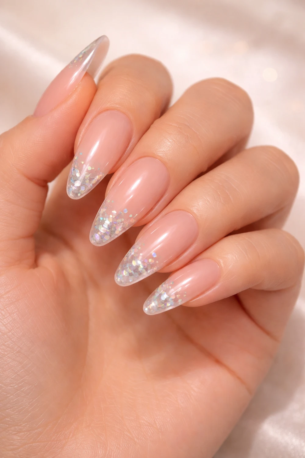 Glitter ombre acrylic nails with nude base fading into sparkling silver tips creating a soft glamorous manicure perfect for elegant nail inspiration.