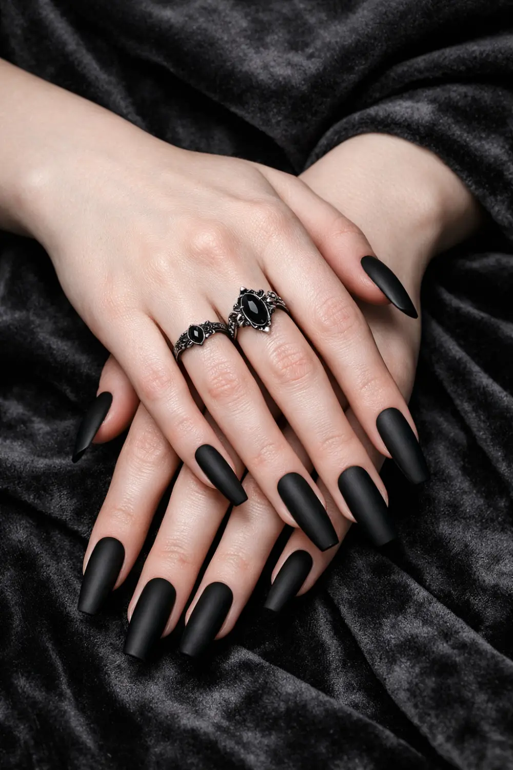 Matte black gothic coffin nails on elegant hands with dark rings, long coffin shaped manicure, minimalist gothic nail design perfect for dark glam aesthetic and edgy nail inspo.