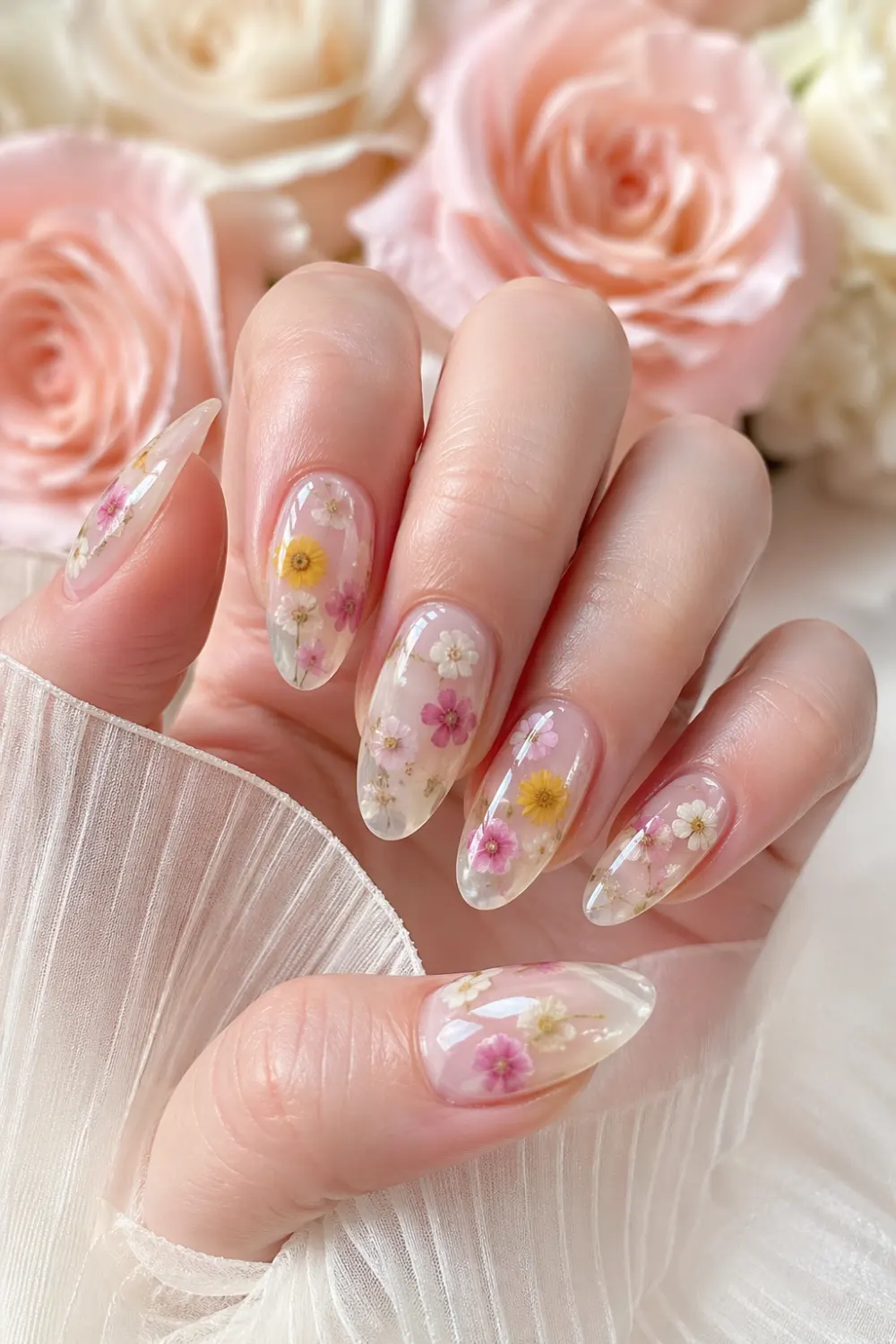 floral milk bath nails with dried flowers embedded in sheer milky base glossy almond shape nails soft pink yellow white flowers delicate feminine manicure 2026 aesthetic nail trend
