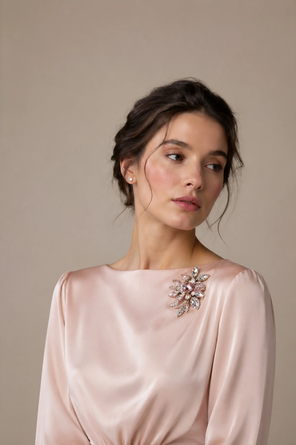 Elegant female model wearing a blush satin dress with a vintage floral crystal brooch pinned near the collarbone, soft studio lighting, glowing skin, delicate sparkle, romantic high-end fashion styling for 2026