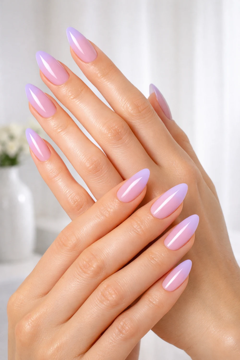 Close-up of slim feminine hands with almond-shaped nails featuring a soft pink to lavender ombre gradient, glossy finish, smooth skin, bright airy background, ultra-clean pastel manicure aesthetic