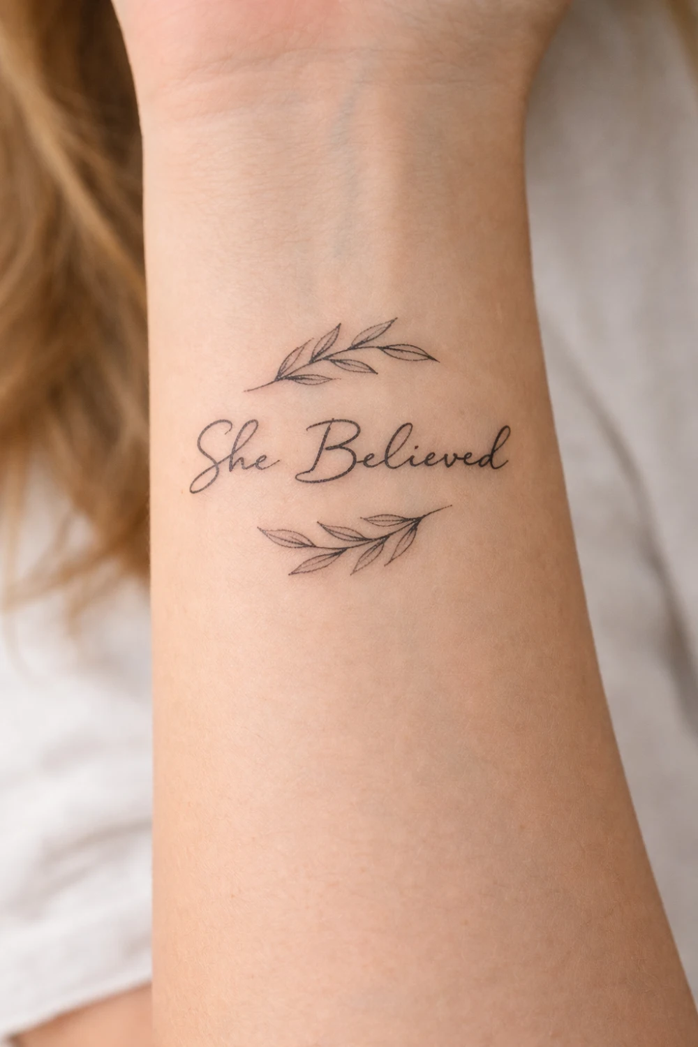 She Believed forearm script tattoo for women with delicate leaf branches symbolizing self confidence strength and empowerment, inspirational tattoo trending on Pinterest.