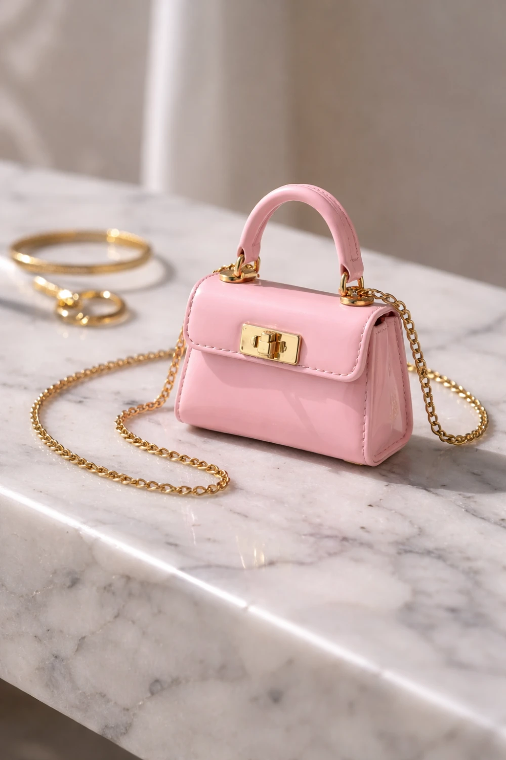 Tiny pink micro mini handbag with gold chain strap placed on marble surface with jewelry, trendy mini bag accessory for women fashion 2026.