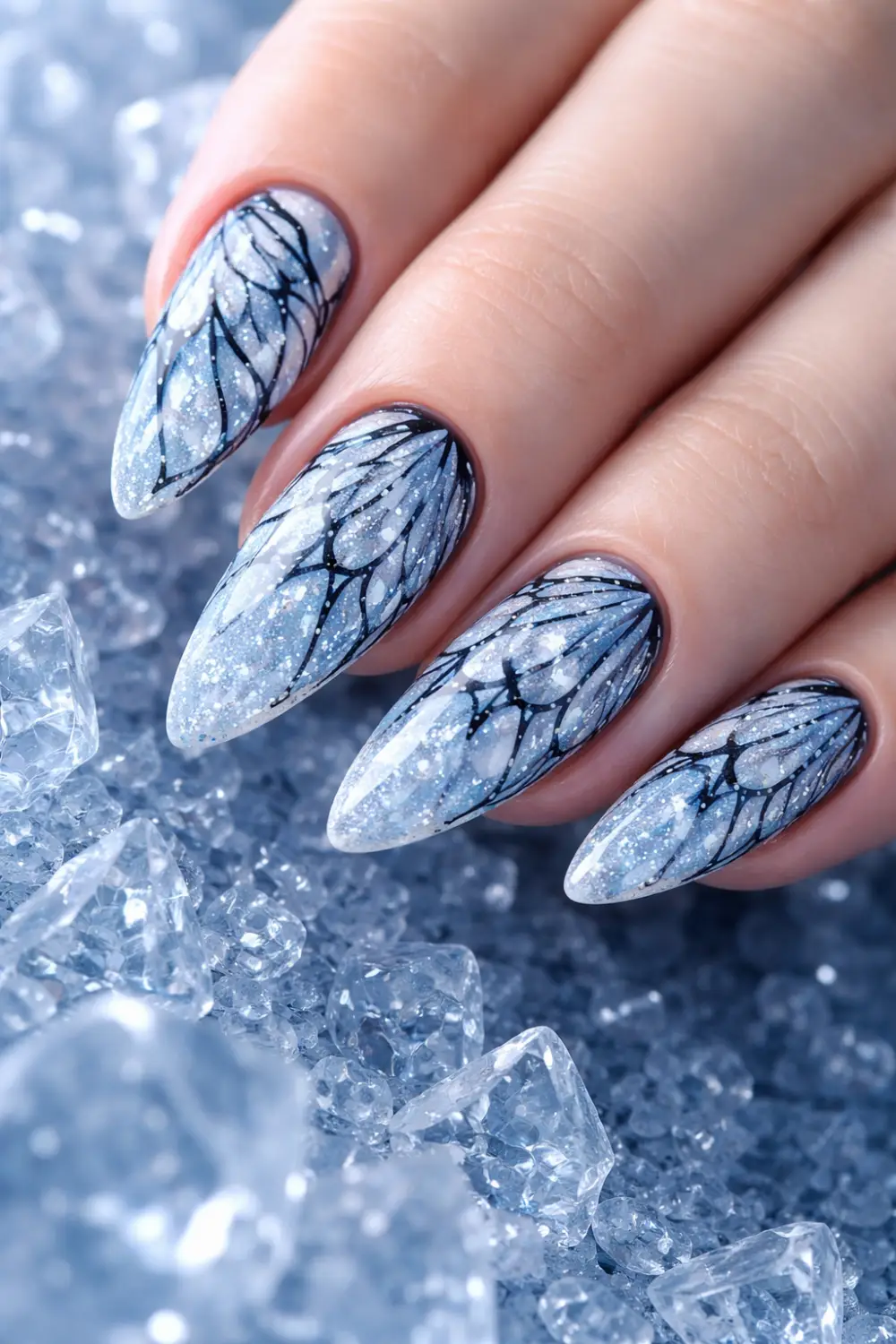 Full female hand on icy crystals showing ice blue butterfly wing nail art with silver shimmer and glossy gel manicure elegant butterfly nail inspiration