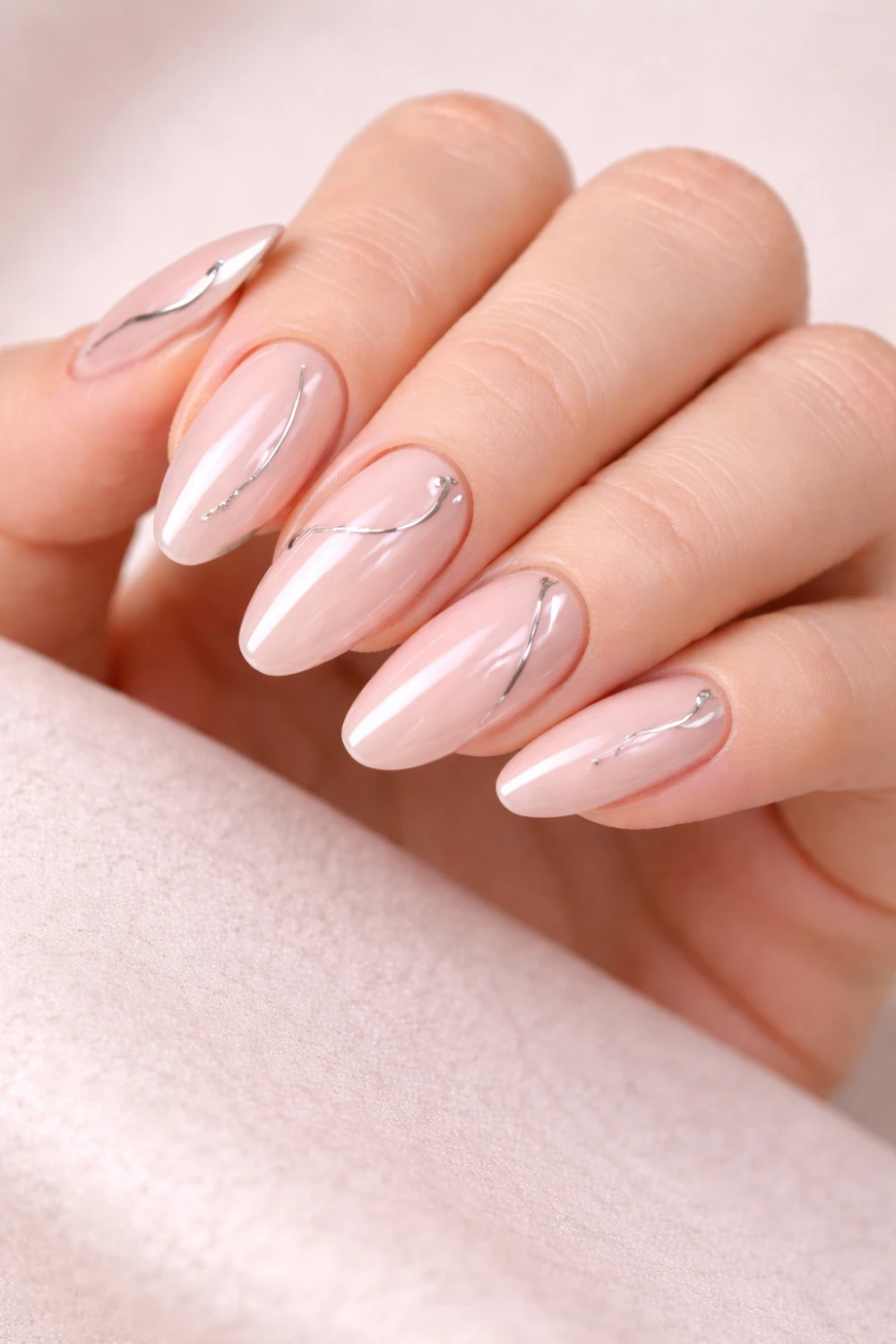 Minimal nude nails with thin chrome accent lines on almond manicure, glossy soft pink base with delicate metallic nail art details, minimalist chrome nail inspiration