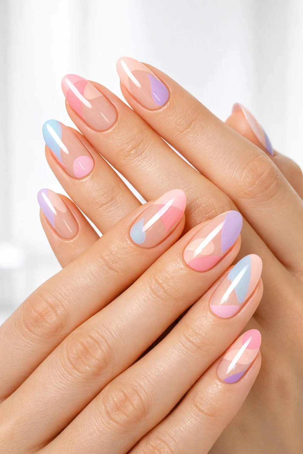 Nude base nails with abstract pastel shapes in pink, blue, and lavender on slim feminine hands, glossy finish, modern artistic nail design