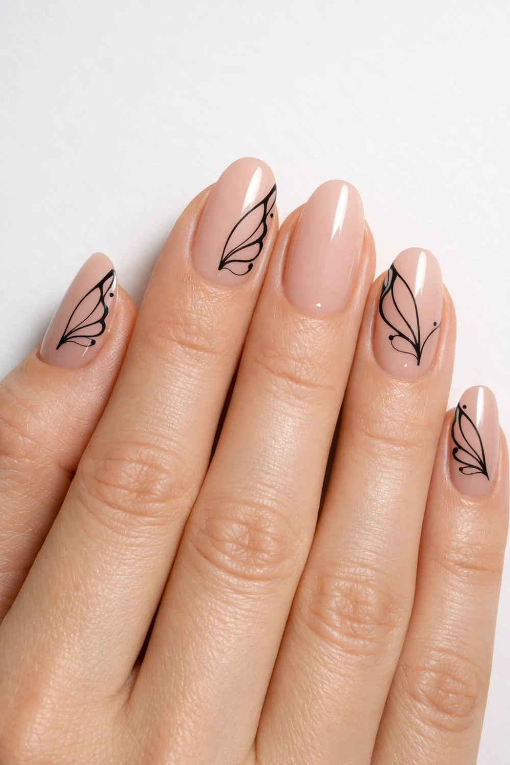 Full female hand on clean white background showing minimal butterfly wing nail art with nude base and black wing line details glossy gel manicure inspiration