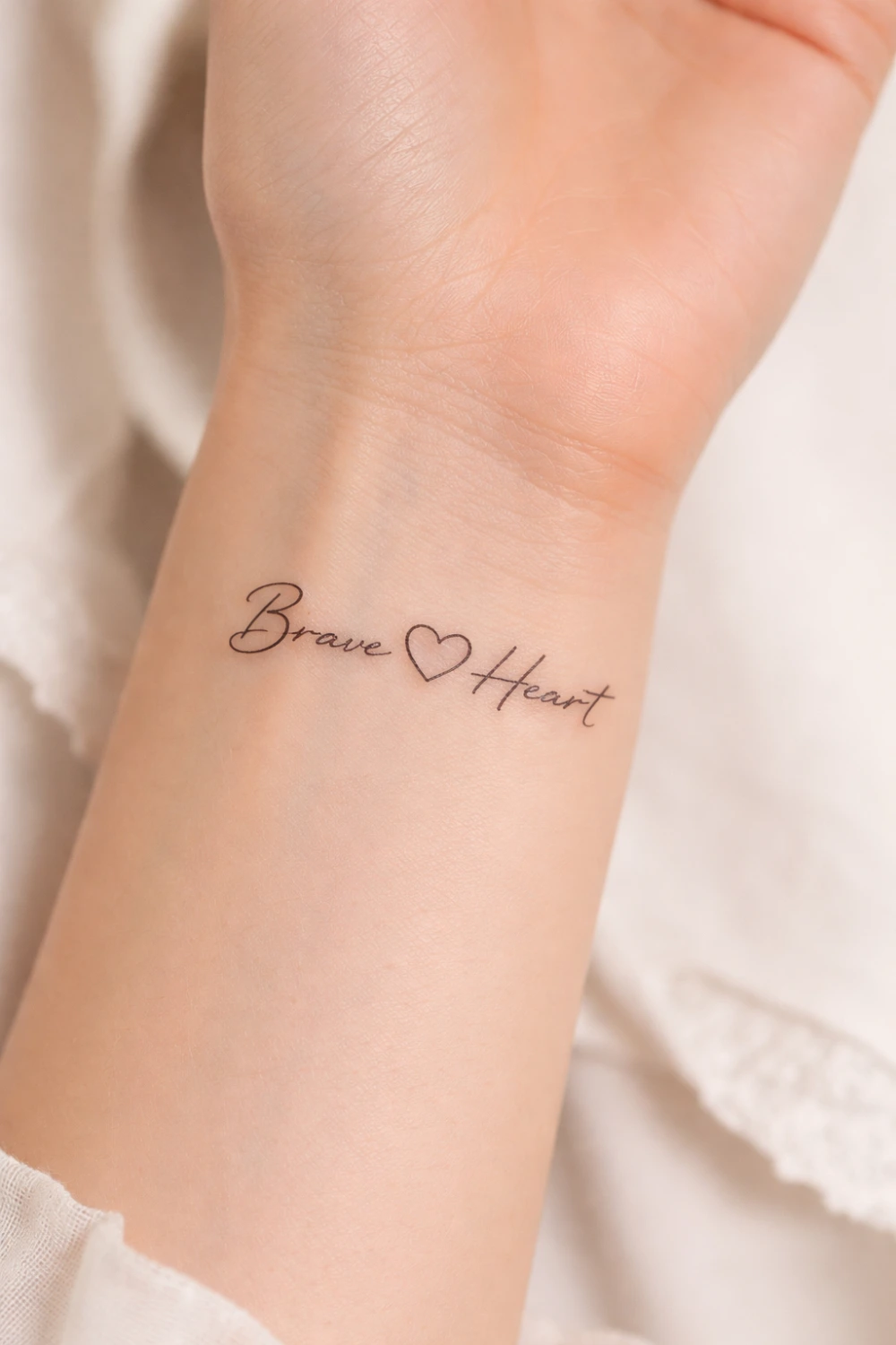 Brave Heart wrist script tattoo for women with small heart symbol representing courage love and emotional strength, inspirational tattoo idea trending on Pinterest.