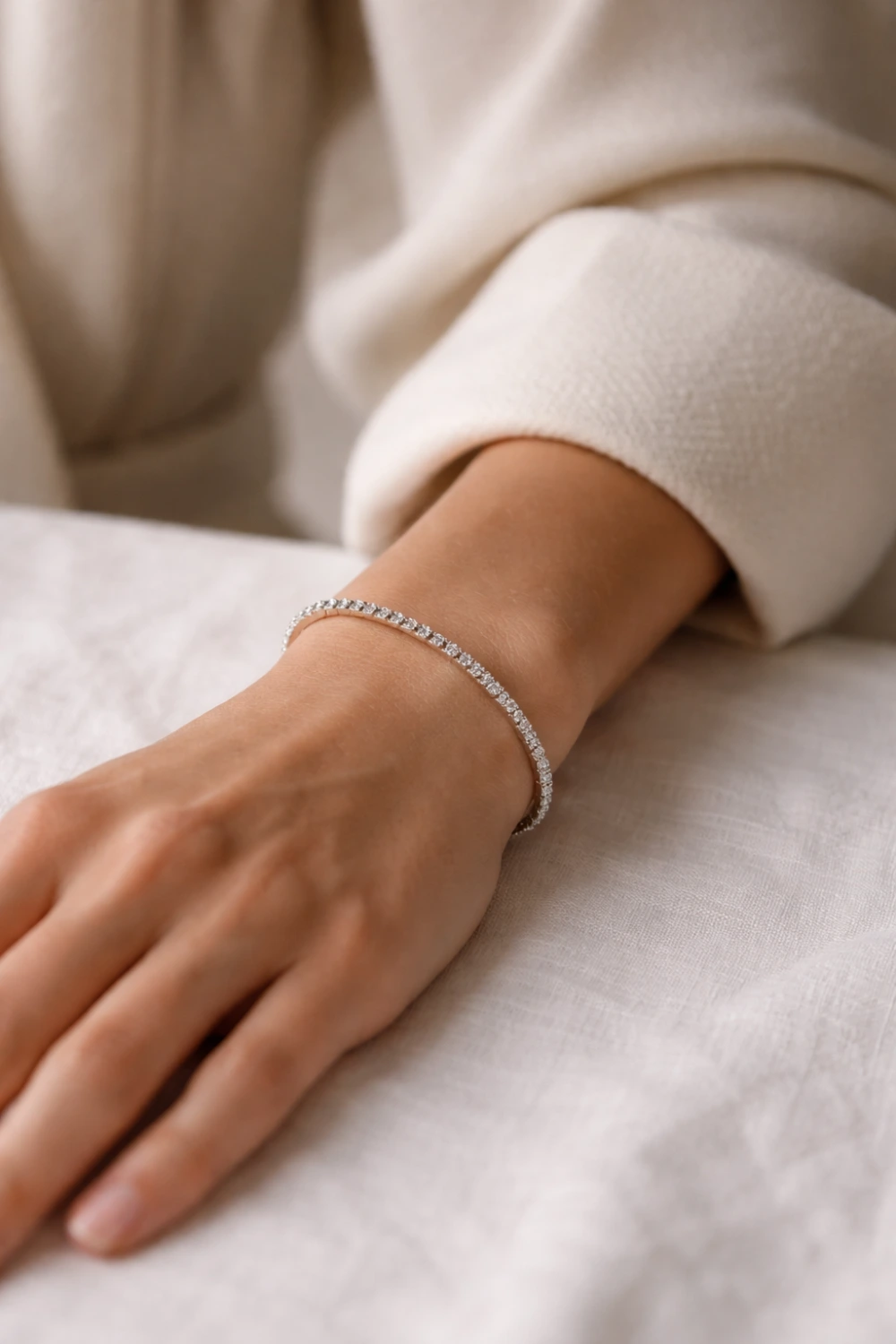 Close up of a woman's wrist wearing a delicate diamond tennis bracelet with neutral outfit styling, capturing a classic old money jewelry look that feels refined, elegant, and quietly luxurious.