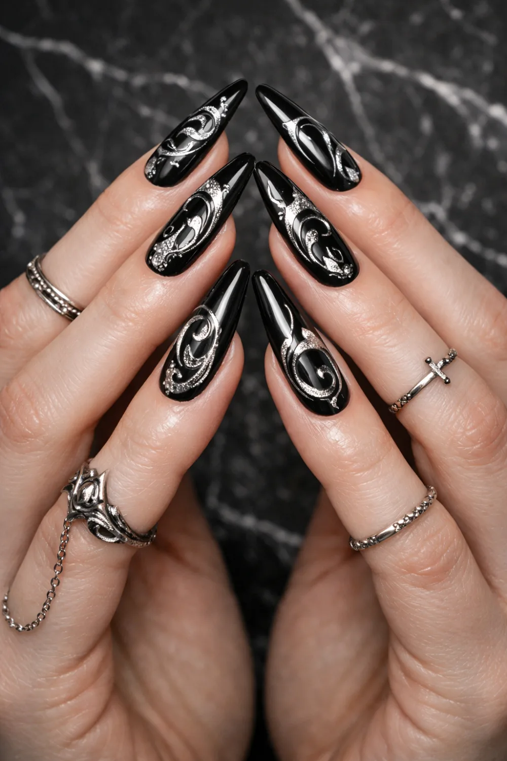 Black coffin nails with silver gothic swirl nail art on glossy manicure, long dramatic coffin nails with gothic rings, dark glam nail design perfect for gothic aesthetic lovers.