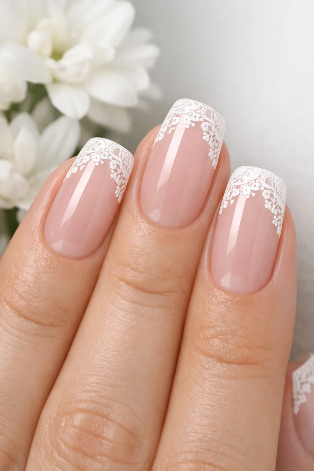 Classic french manicure with delicate lace nail tips on a soft pink nude base, elegant short nails featuring intricate white lace patterns along the tip creating a classy bridal inspired lace nail design perfect for minimalist nail inspiration