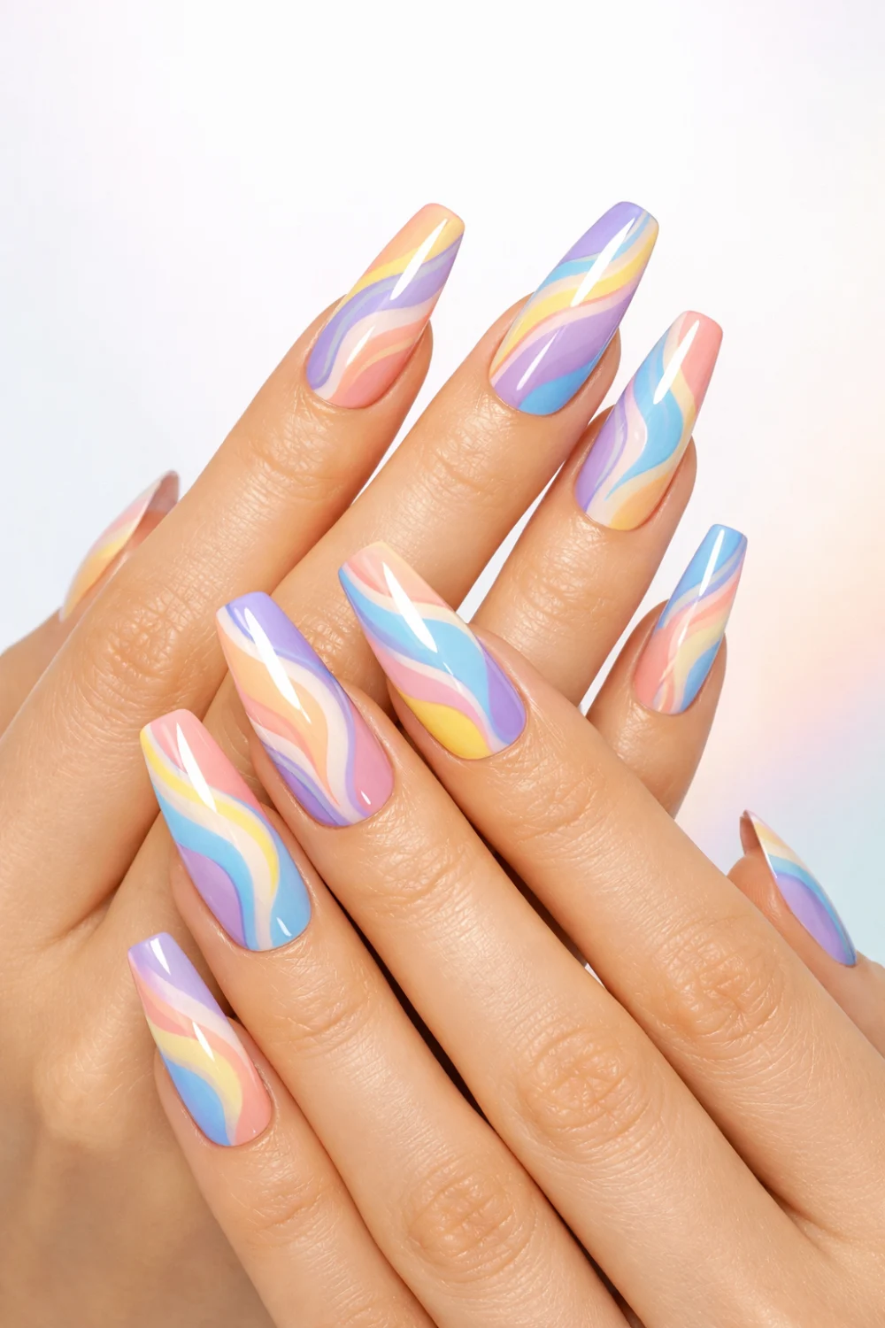 Long coffin-shaped nails with pastel swirl nail art in pink, blue, yellow, and lavender tones on slim feminine hands, glossy finish, clean bright background