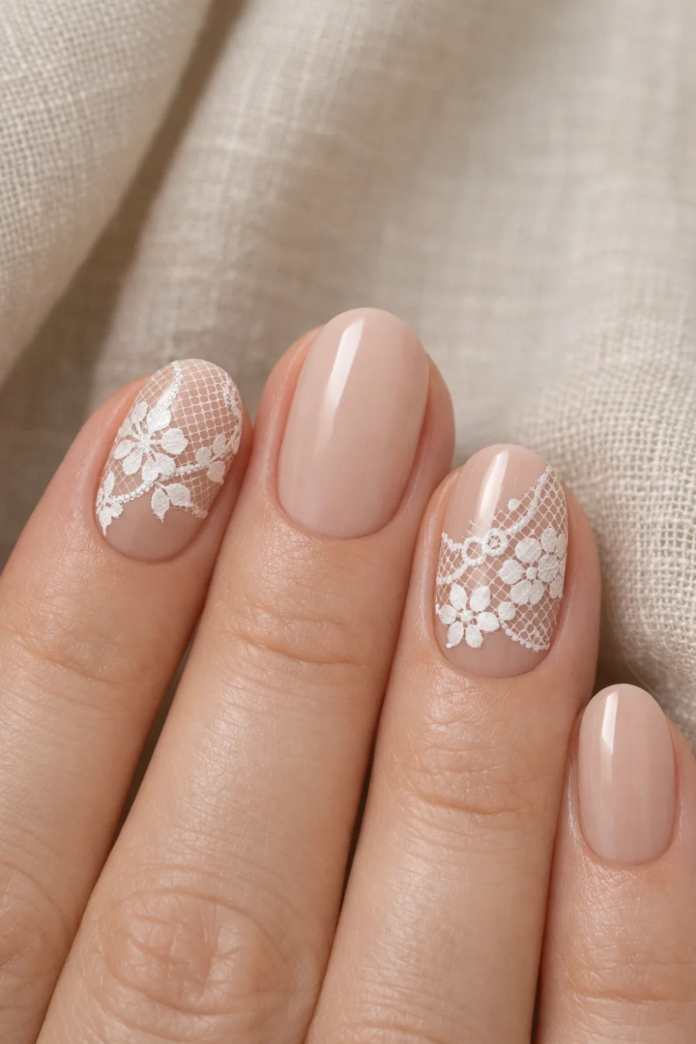 Soft nude manicure with delicate white lace nail art and subtle floral patterns over natural beige polish, elegant short oval nails creating a minimal classy lace nail design perfect for everyday manicure inspiration and bridal nails