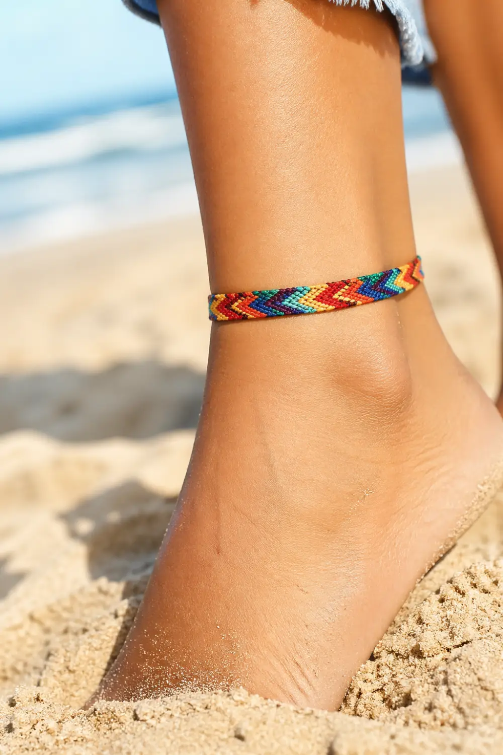 colorful thread anklet woven pattern on ankle beach sand vibrant boho style friendship anklet summer aesthetic close up