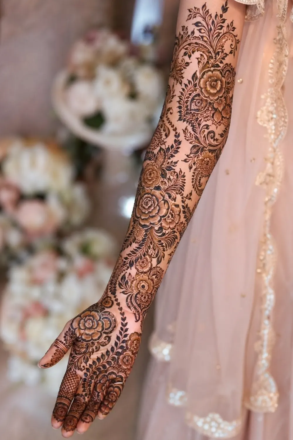 heavy floral full sleeve mehndi design with roses, leaves, and dense patterns covering entire arm, detailed bridal henna with smooth flow, rich traditional look from fingers to elbow, soft lighting