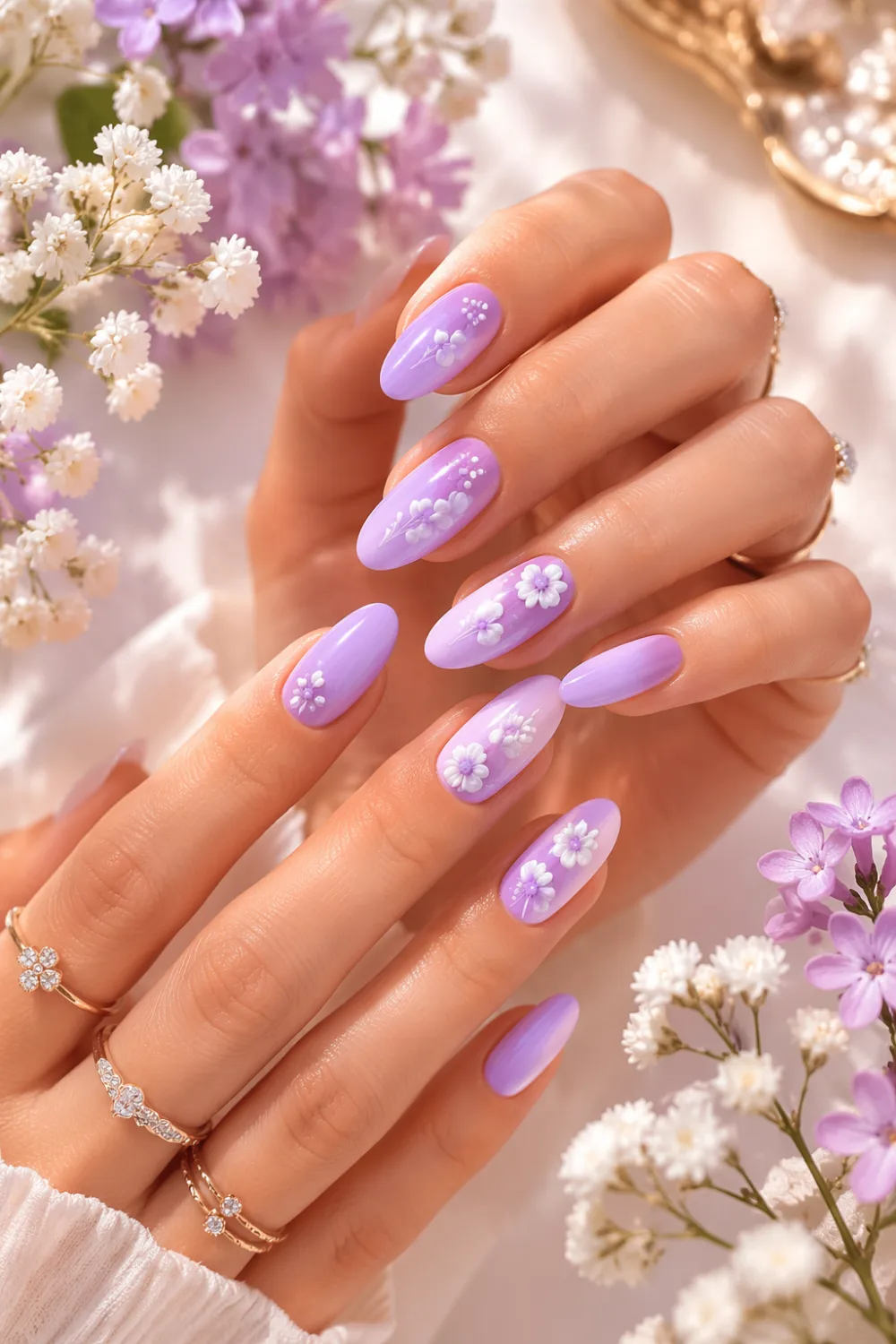 Almond-shaped lilac pastel nails with tiny white floral accents on feminine hands, glossy finish, soft floral background, delicate spring nail design