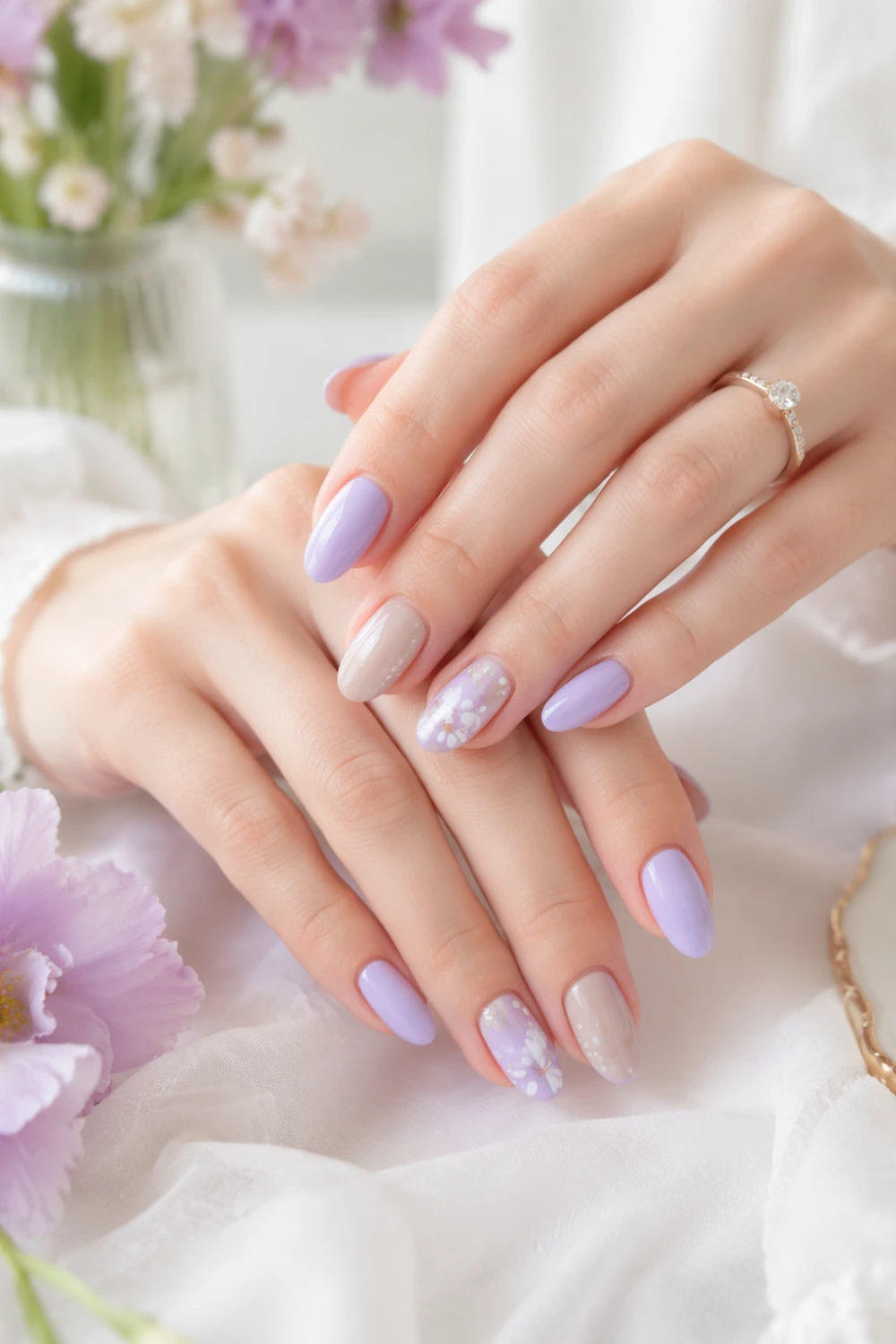 Elegant hands with mixed pastel nails in lilac and nude tones featuring floral accents, glossy finish, soft aesthetic background, trendy nail design