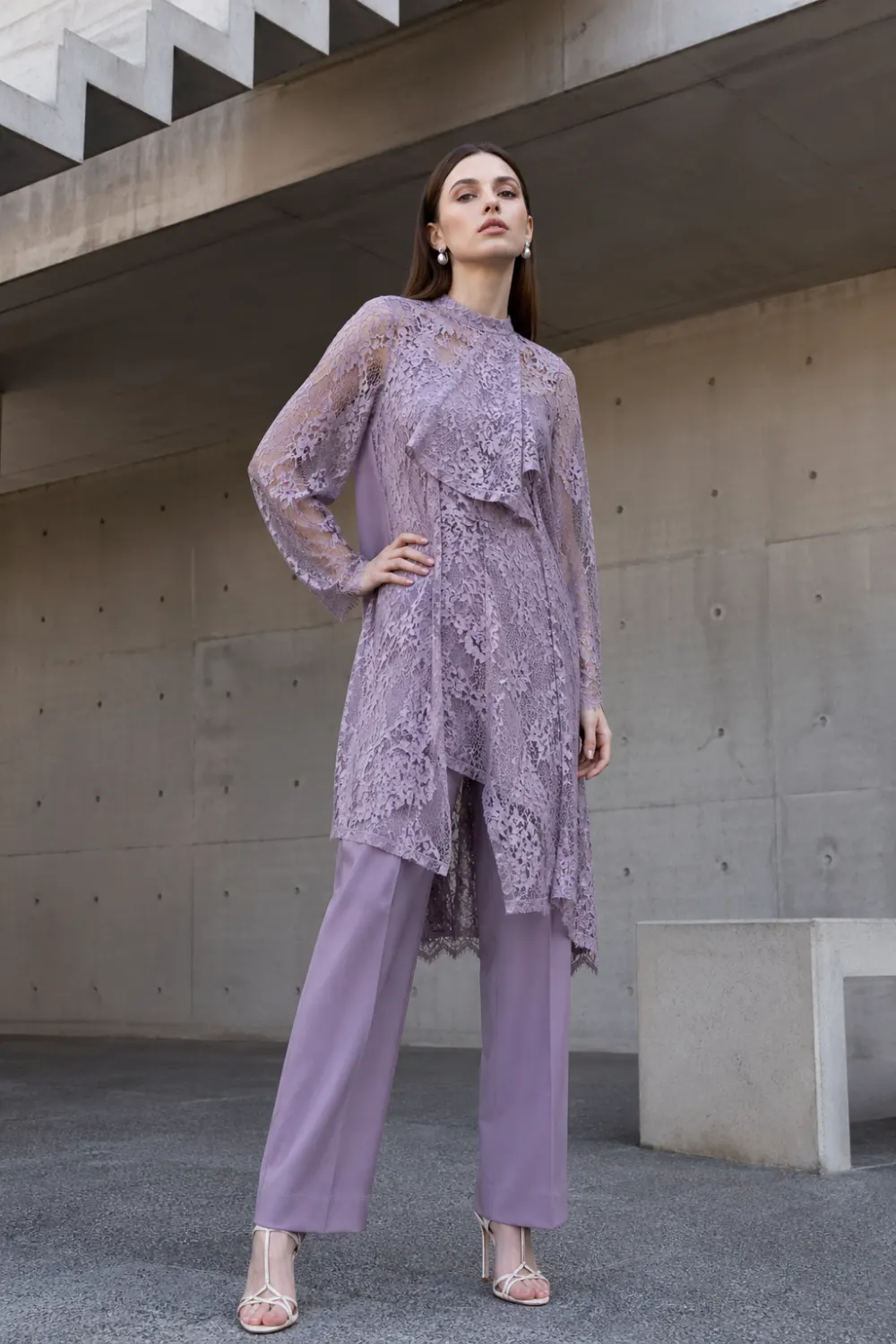 lavender lace tunic with tailored pants outfit, modern layered lace fashion look, structured feminine outfit, elegant minimal architecture background style, chic contemporary outfit
