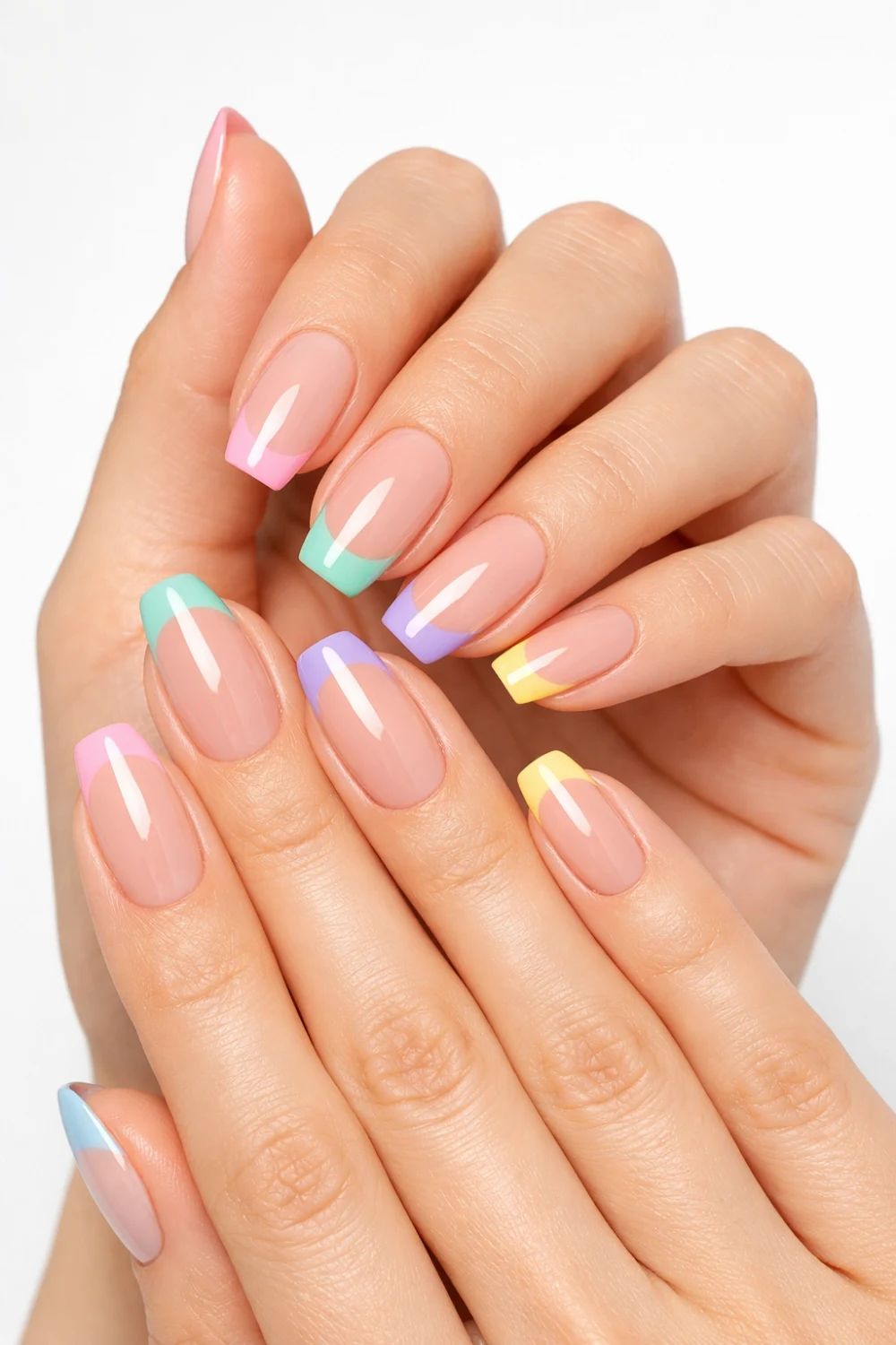 Nude base nails with pastel rainbow French tips in pink, mint, lavender, and yellow on feminine hands, glossy finish, clean minimal background