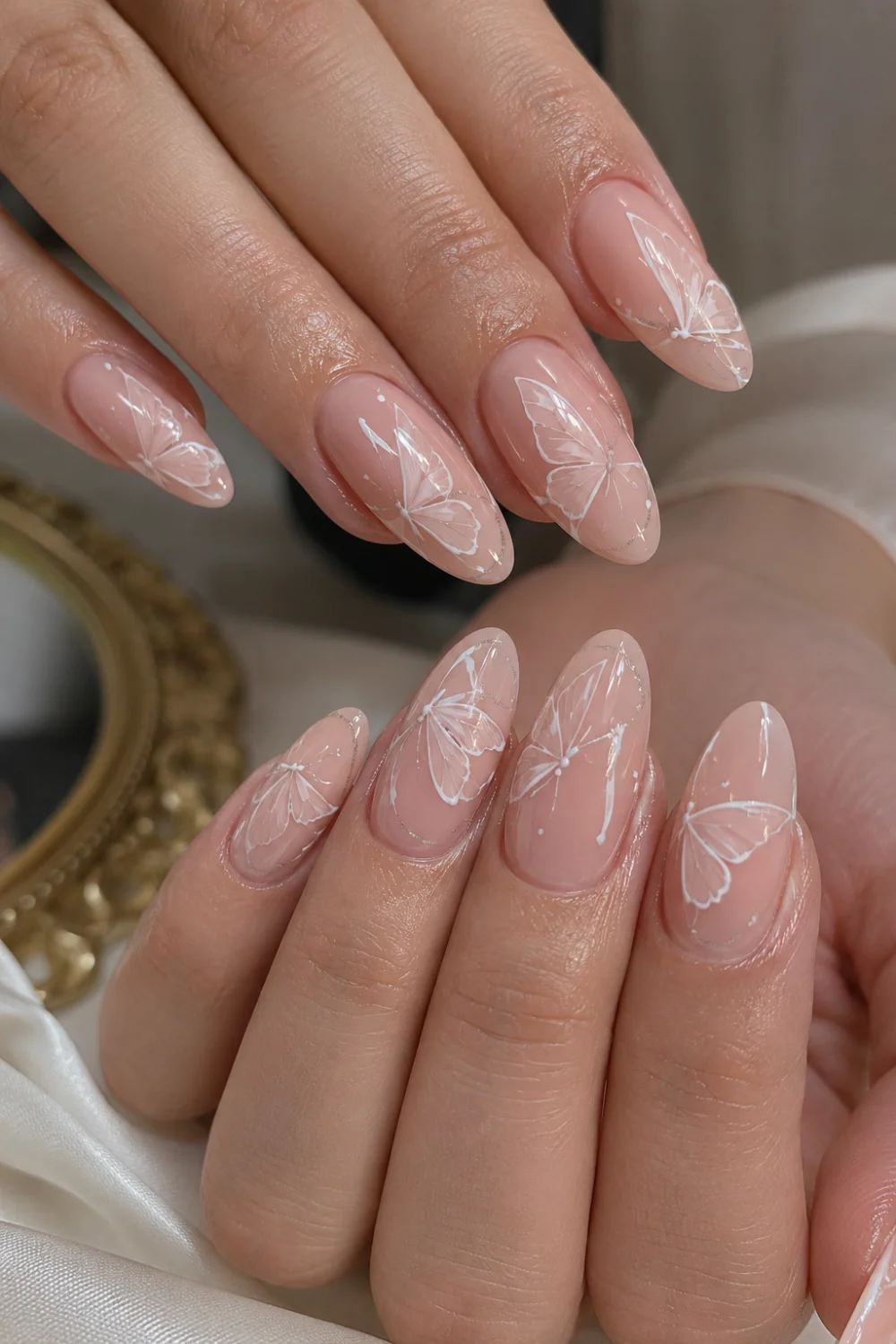 Soft pink glossy almond nails with delicate white butterfly nail art, nude pink gel polish, and elegant feminine salon-style manicure with classy butterfly wing details and shiny glossy finish.