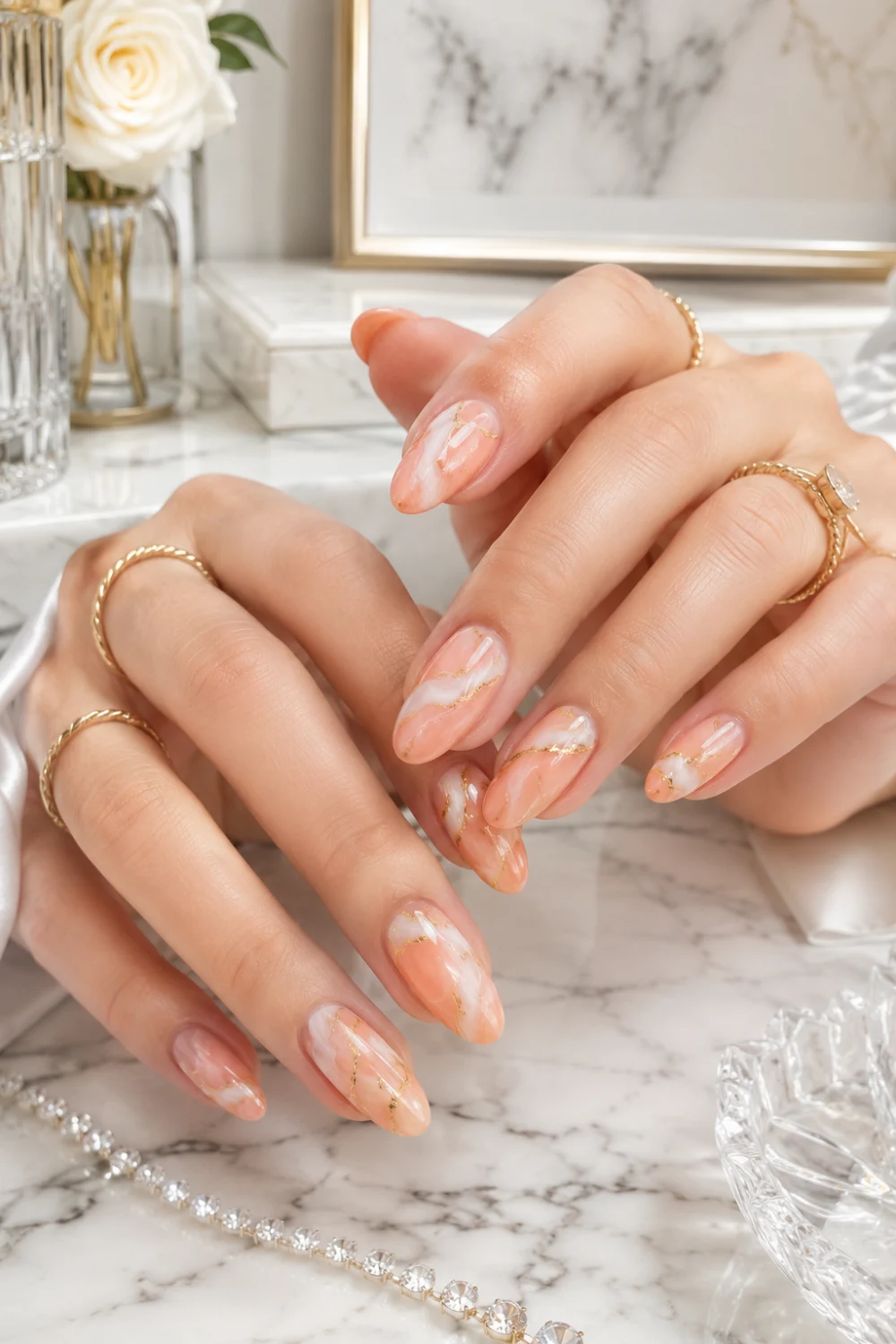 Peach marble gold nails with glossy almond manicure, luxury gold accents, feminine hands, and elegant marble nail art aesthetic