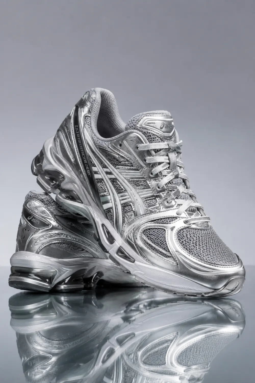 Silver ASICS gel-tech runner women sneakers with futuristic sporty aesthetic, chunky cushioned sole, and metallic mesh details styled for trendy athleisure outfits and streetwear fashion.