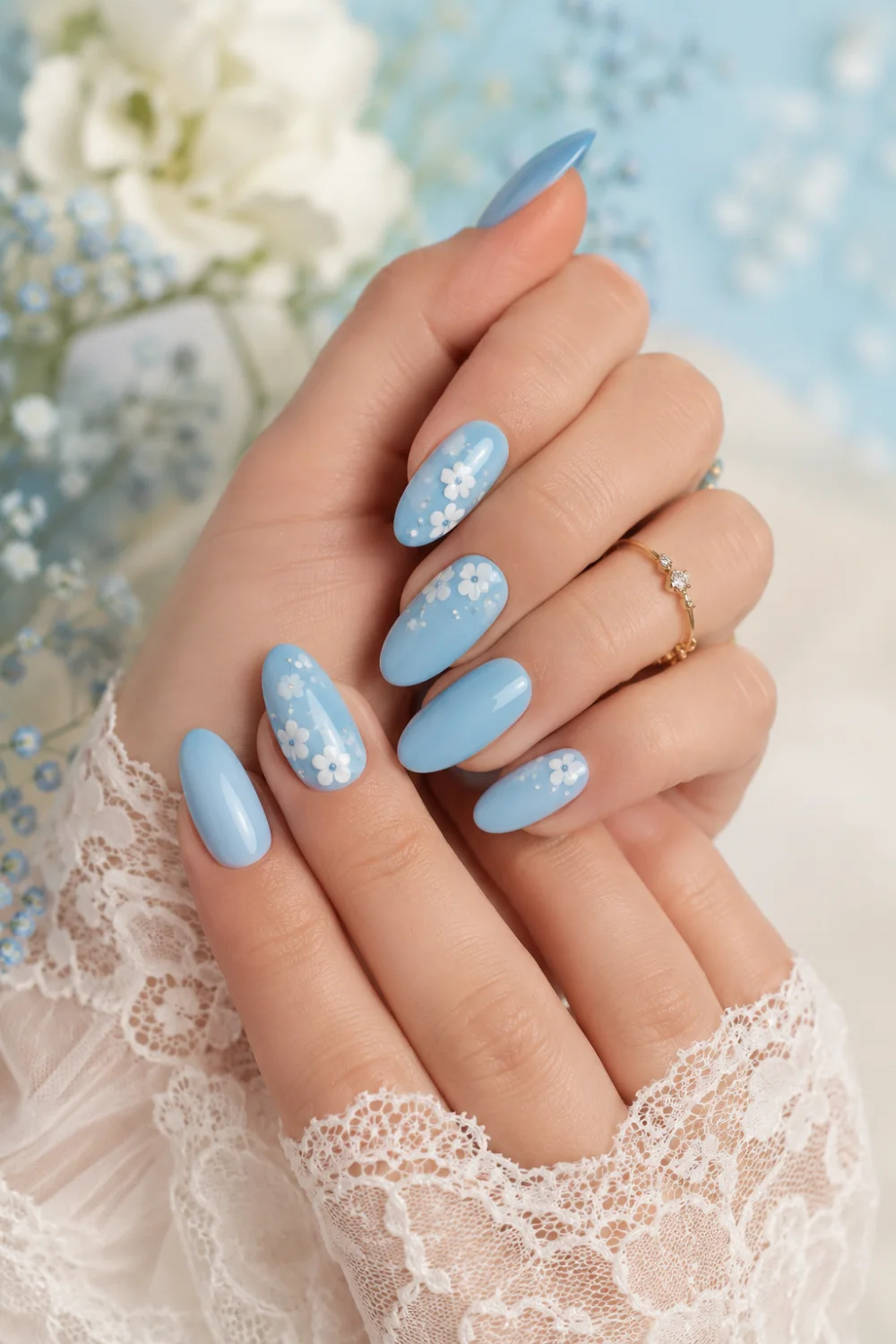 Sky blue floral almond nails with tiny white flower nail art, glossy feminine manicure featuring soft spring Pinterest-inspired beauty aesthetic.