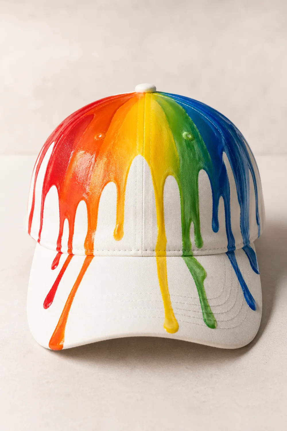 White hand painted cap with rainbow paint drip design, colorful modern DIY painted hat aesthetic