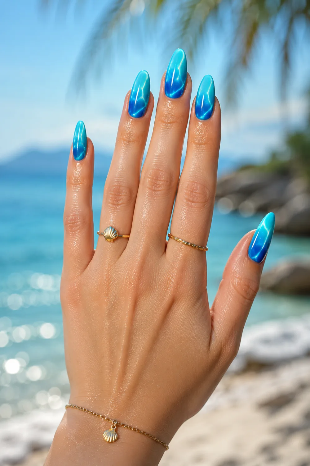 Blue ocean ombre nails with aqua and deep sea gradient on glossy almond nails, featuring beach-inspired manicure styling, gold jewelry, and tropical summer nail trends for 2026.
