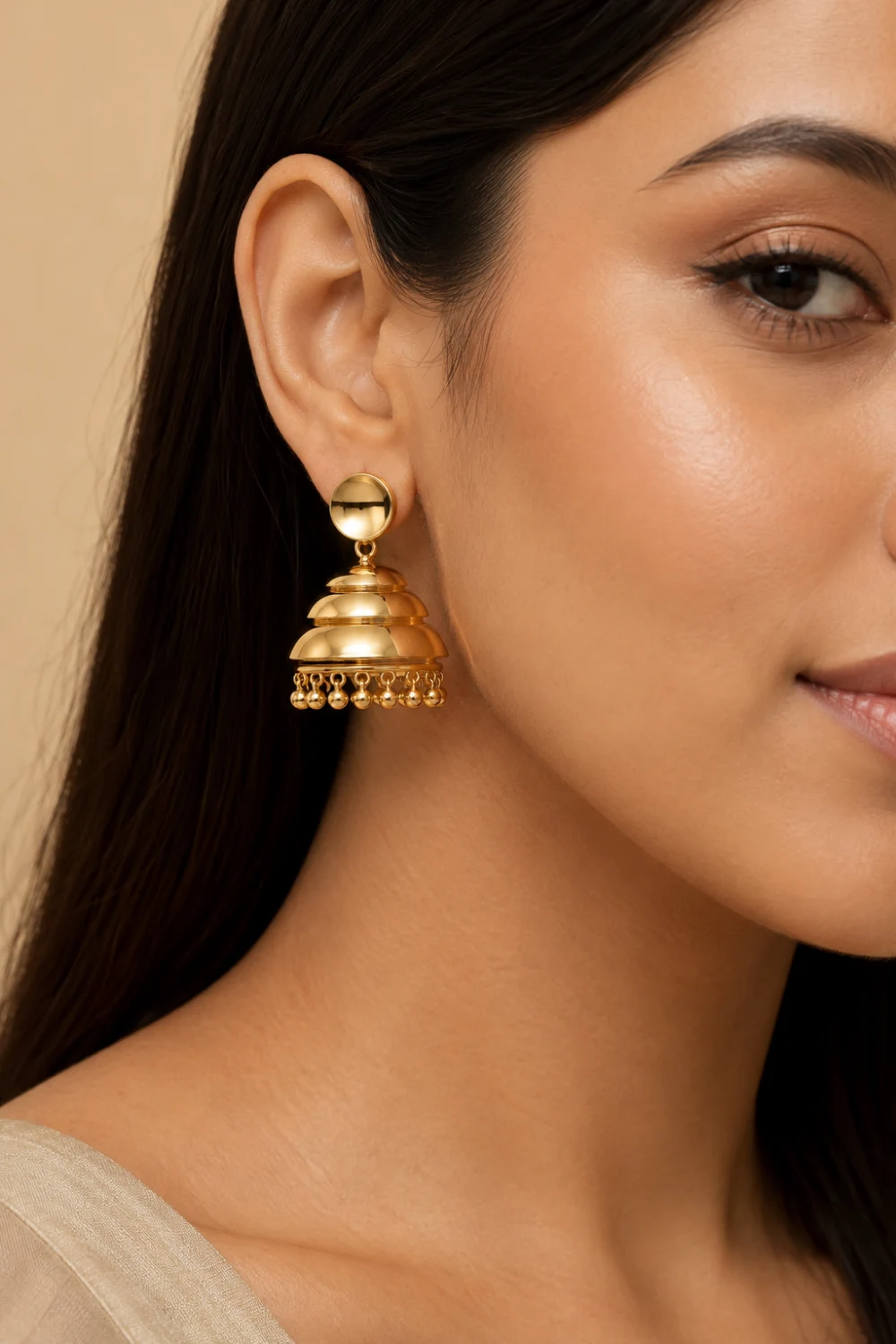 Elegant woman wearing minimal layered gold jhumka earrings with sleek glossy finish, modern dome design, lightweight luxury styling, and clean contemporary ethnic fashion aesthetic