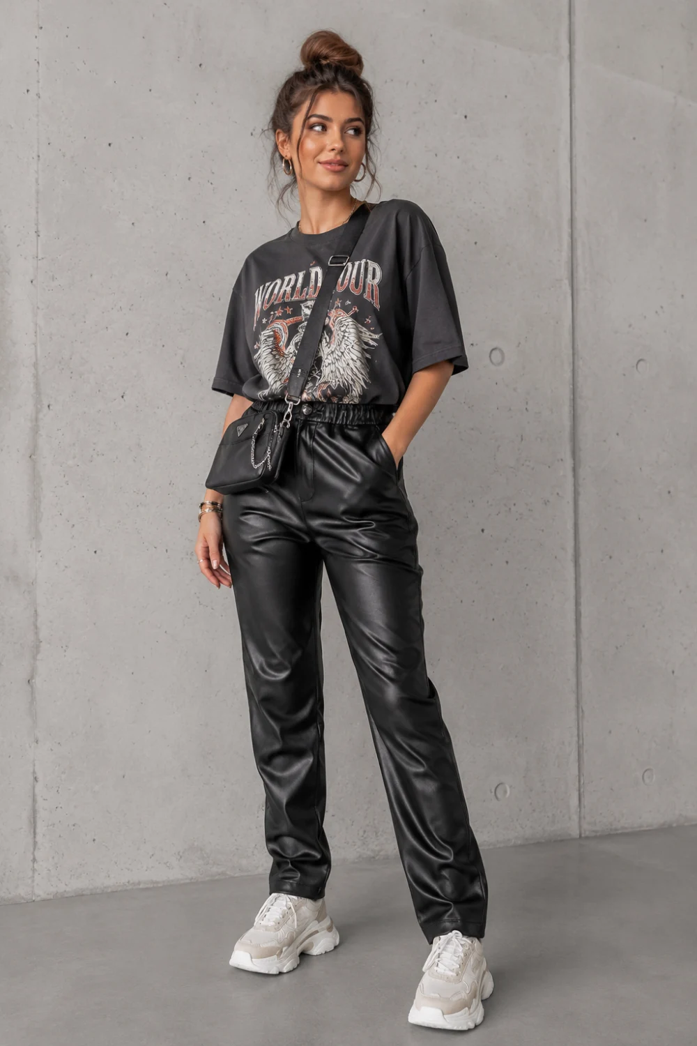 Cute stylish woman wearing oversized graphic tee with black faux leather pants and chunky sneakers, edgy casual night out outfit idea, trendy street style fashion for women, cool concert outfit aesthetic with modern urban fashion vibe.