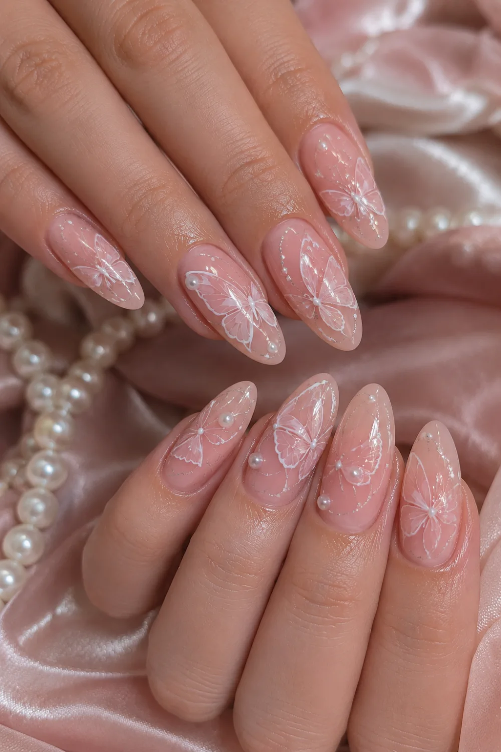 Pearl pink glossy almond nails with delicate white butterfly nail art, soft feminine manicure design, pearl accents, and elegant salon-style glossy butterfly nails.