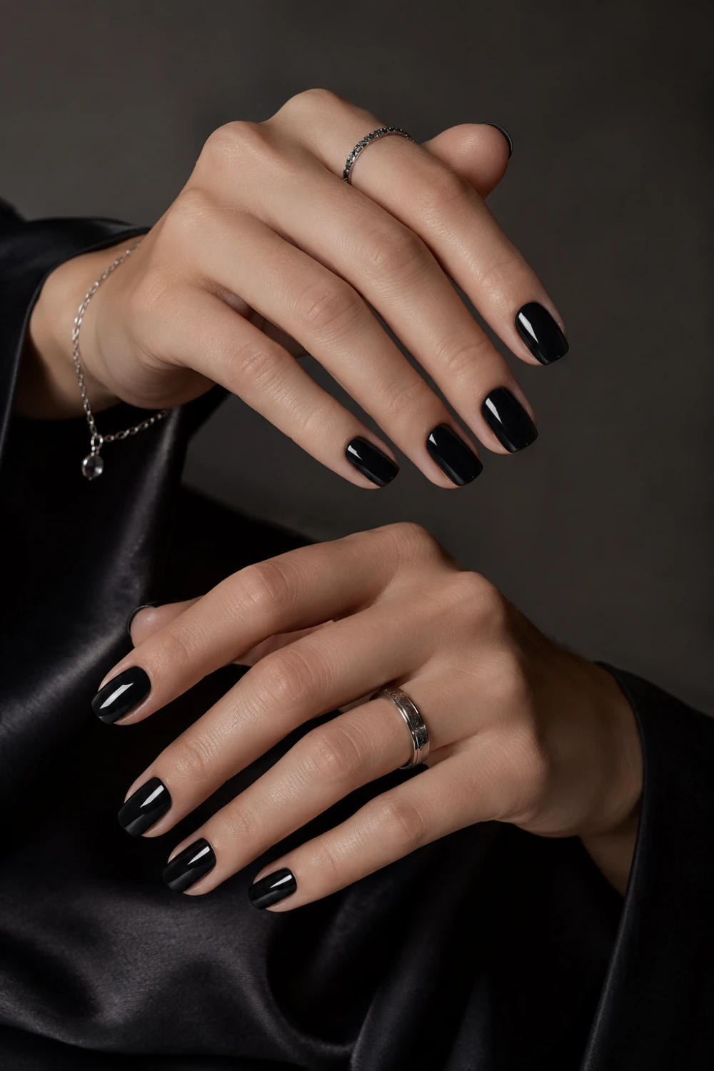 Glossy black short nails with sleek luxury manicure styling, silver jewelry accents, dark satin background, and ultra modern feminine beauty aesthetic.
