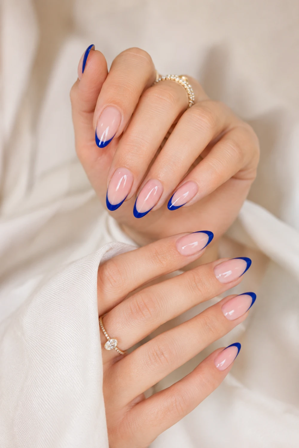 Royal blue French tip almond nails with glossy nude base, classy blue manicure design featuring elegant minimalist nail art and trendy Pinterest beauty style.