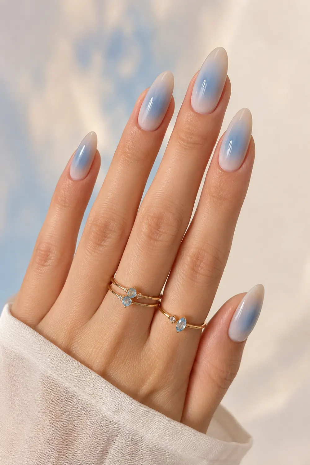 Soft blue aura almond nails with dreamy gradient effect, glossy pastel manicure featuring milky blue tones and elegant clean girl Pinterest-inspired aesthetic.