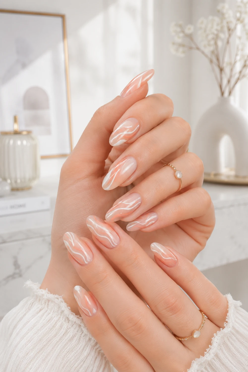 Peach swirl nail art with glossy almond nails, abstract white swirl details, feminine hands, and modern clean girl aesthetic