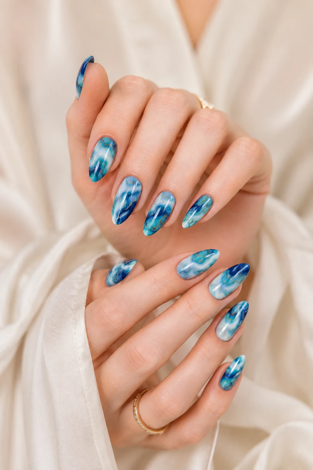 Ocean marble blue almond nails with turquoise, navy, and white swirl details, artistic glossy manicure design inspired by luxury Pinterest nail trends.