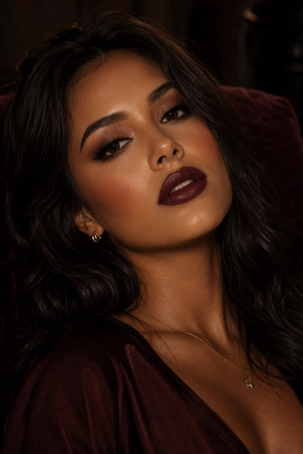 Luxury beauty portrait featuring warm cocoa plum lips with rich brown berry tones, bronzed glowing skin, soft smoky eye makeup, glossy dark hair, and cozy elegant beauty styling. Romantic dark feminine makeup aesthetic with cinematic warm lighting and sophisticated plum lipstick inspiration for 2026.