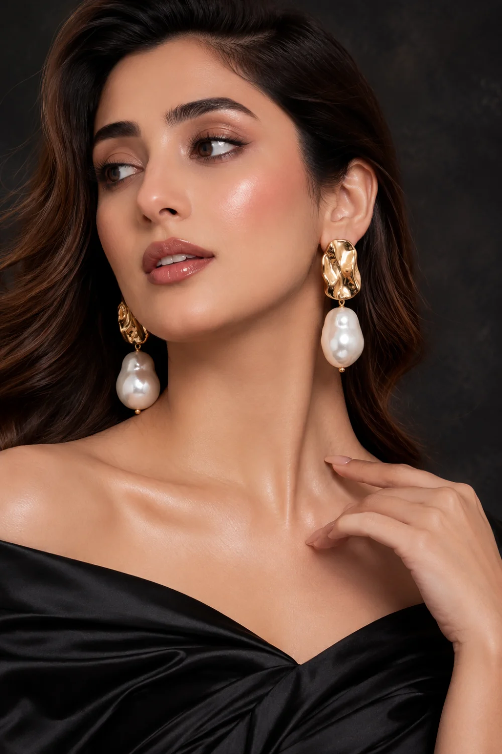 Beautiful woman wearing oversized baroque pearl statement earrings with textured gold settings, luxury black outfit, elegant makeup, and modern pearl jewelry styling for 2026 fashion trends.