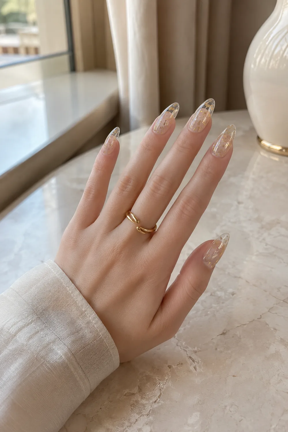 Clear jelly almond nails with gold foil accents, transparent gel finish, luxury nail art details, glossy shine, and an elegant minimalist manicure design.