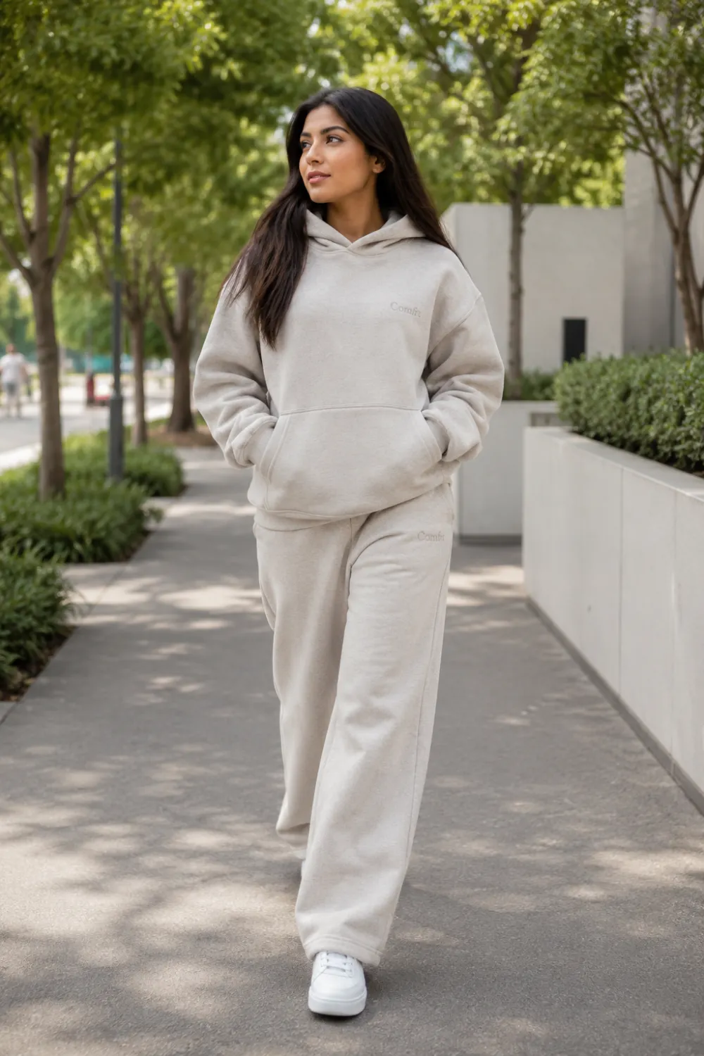 Woman wearing an oversized hoodie with matching wide leg sweatpants and white sneakers while walking outdoors. Comfortable oversized athleisure outfit featuring neutral tones, casual fashion, and cozy everyday style inspiration.